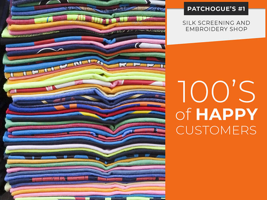Stacks of colorful folded t-shirts next to an orange banner reading "100's of HAPPY CUSTOMERS" and promoting a silk screening and embroidery shop in Patchogue.